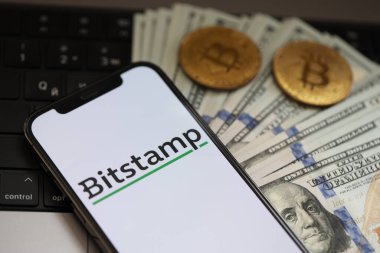 KYIV, UKRAINE - 15 Mart 2024 Bitstamp logosu iPhone ekranında dolar ve bitcoin ile MacBook üzerinde. Kripto döviz portalı