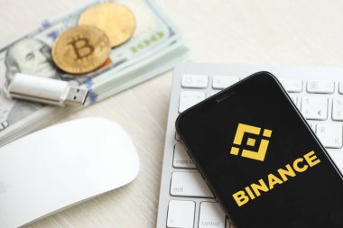 KYIV, UKRAINE - 15 Mart 2024 Binance logosu iPhone ekranında beyaz klavyede para ve bitcoin ile. Kripto döviz portalı