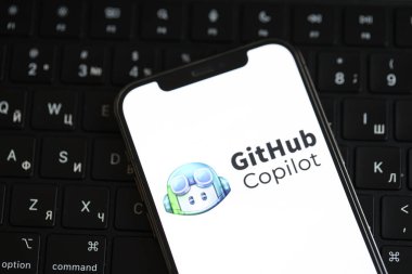 KYIV, UKRAINE - 17 Mart 2024 Github yardımcı pilot logosu iPhone ekran ve MacBook klavyesinde. Yapay Zeka Motoru