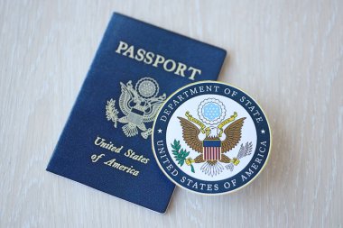 KYIV, UKRAINE - 9 Mart 2024 ABD Dışişleri Bakanlığı mührü ve ABD pasaportu ahşap masaya yakın.