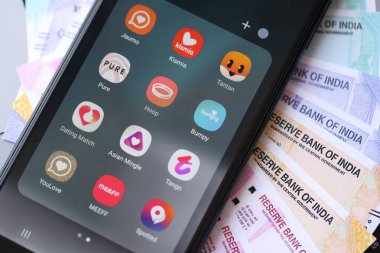 KYIV, UKRAINE - 28 Şubat 2024 MacBook klavyesinde akıllı telefon ekran simgeleri ve Hint rupileri para faturaları