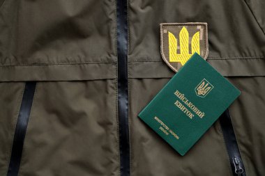 Military token or army ID ticket lies on green ukrainian military uniform indoors close up clipart