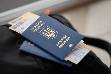 Siyah turistik sırt çantası üzerinde uçuş biletleri olan iki Ukrayna biyometrik pasaportu.