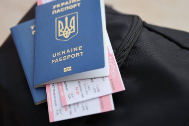 Siyah turistik sırt çantası üzerinde uçuş biletleri olan iki Ukrayna biyometrik pasaportu.