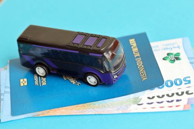 Blue Republic Indonesia passport with money and toy bus on blue background close up. Tourism and travel concept clipart