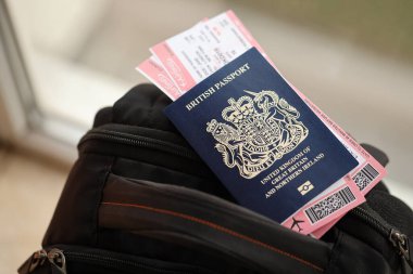 Turistik sırt çantasında uçak biletleri olan mavi İngiliz pasaportu. Turizm ve seyahat kavramı