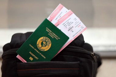 Turistik sırt çantası üzerinde uçak biletleri olan yeşil Nijerya pasaportu. Turizm ve seyahat kavramı