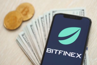 KYIV, UKRAINE - 15 Mart 2024 Btfinex logosu iPhone ekranında dolar ve bitcoin ile. Kripto döviz portalı
