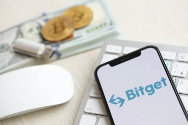 KYIV, UKRAINE - 15 Mart 2024 Bitget logosu iPhone ekranında beyaz klavyede para ve bitcoin ile. Kripto döviz portalı