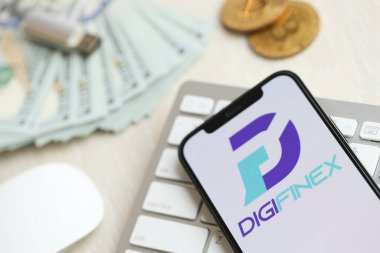 KYIV, UKRAINE - 15 Mart 2024 Digifinex logosu iPhone ekranında para ve bitcoin ile birlikte beyaz klavyede. Kripto döviz portalı
