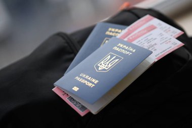 Siyah turistik sırt çantası üzerinde uçuş biletleri olan iki Ukrayna biyometrik pasaportu.