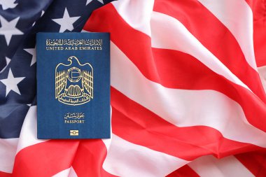 Blue United Arab Emirates passport on United States national flag background close up. Tourism and diplomacy concept clipart