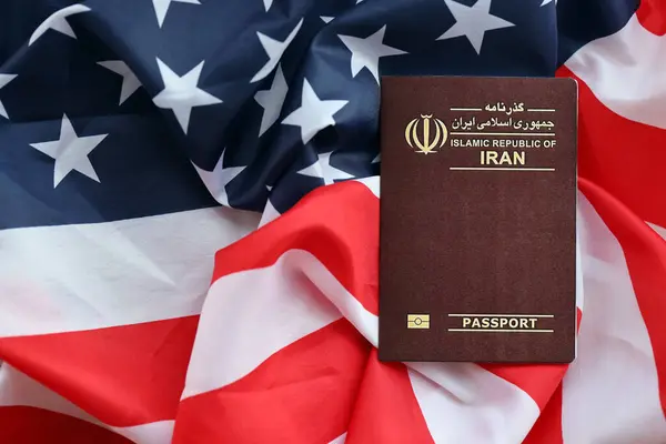 Stock image Red Islamic Republic of Iran passport on United States national flag background close up. Tourism and diplomacy concept