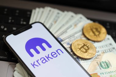 KYIV, UKRAINE - 15 Mart 2024 Kraken logosu iPhone ekranında dolar ve bitcoin ile MacBook. Kripto döviz portalı