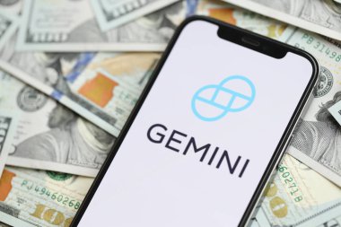 KYIV, UKRAINE - 15 Mart 2024 Gemini logosu iPhone ekranında yüzlerce dolarlık banknotlarla. Kripto döviz portalı