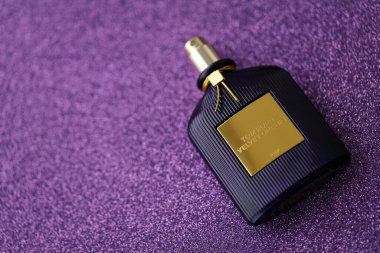 KYIV, UKRAINE - 27 Kasım 2023 Tom Ford kadife orkide parfüm şişesi açık leylak arka planda yatar. Tom Ford, Amerikalı moda tasarımcısı. 2006 'da ünlü lüks markasını kurdu.