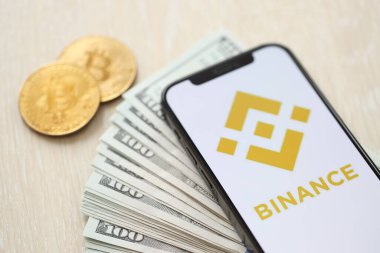 KYIV, UKRAINE - 15 Mart 2024 Binance logosu iPhone ekranında dolar ve bitcoin ile birlikte. Kripto döviz portalı