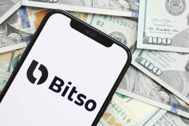 KYIV, UKRAINE - 15 Mart 2024 Bitso logosu iPhone ekranında yüzlerce dolarlık banknotlarla. Kripto döviz portalı