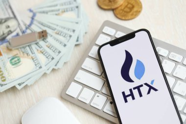 KYIV, UKRAINE - 15 Mart 2024 HTX logosu iPhone ekranında beyaz klavyede para ve bitcoin ile. Kripto döviz portalı