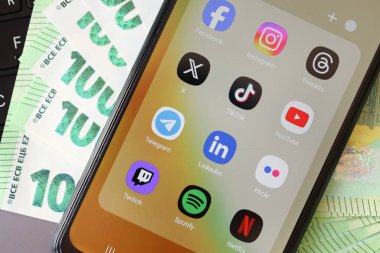 KYIV, UKRAINE - Galaksi A04 'te 28 Şubat 2024 Sosyal Medya simgeleri grubu MacBook klavyesi ve Avro faturaları üzerinde akıllı telefon görüntüsü