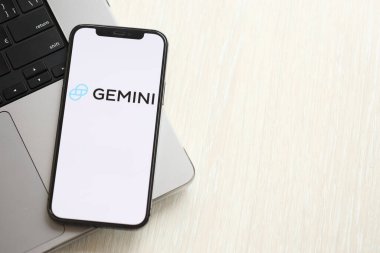 KYIV, UKRAINE - 15 Mart 2024 Gemini logosu MacBook panelinde iPhone ekranında. iPhone ekranında şifreli döviz portalı logosu ve MacBook 'ta dolar ve bitcoin var. Kripto para birimi
