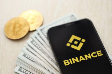 KYIV, UKRAINE - 15 Mart 2024 Binance logosu iPhone ekranında dolar ve bitcoin ile birlikte. Kripto döviz portalı