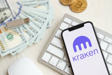KYIV, UKRAINE - 15 Mart 2024 Kraken logosu iPhone ekranında beyaz klavyede para ve bitcoin ile. Kripto döviz portalı