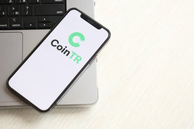 KYIV, UKRAINE - 15 Mart 2024 MacBook panelinde iPhone ekranında CoinTR logosu. iPhone ekranında şifreli döviz portalı logosu ve MacBook 'ta dolar ve bitcoin var. Kripto para birimi