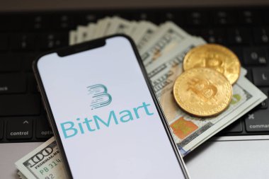 KYIV, UKRAINE - 15 Mart 2024 Bitmart logosu iPhone ekranında dolar ve bitcoin ile MacBook üzerinde. Kripto döviz portalı