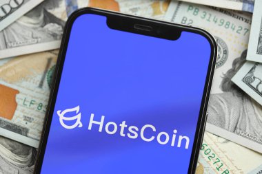 KYIV, UKRAINE - MARCH 15, 2024 Hotscoin logo on iPhone display screen with many hundred dollar bills. Cryptocurrency exchange portal clipart