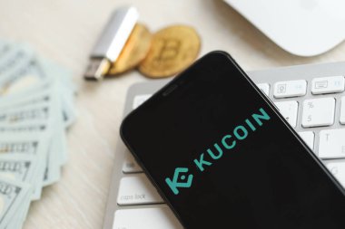 KYIV, UKRAINE - 15 Mart 2024 Kucoin logosu iPhone ekranında beyaz klavyede para ve bitcoin ile. Kripto döviz portalı