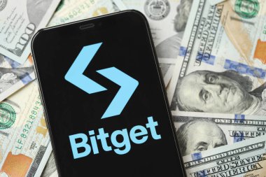 KYIV, UKRAINE - 15 Mart 2024 Bitget logosu iPhone ekranında yüzlerce dolarlık banknotlarla. Kripto döviz portalı