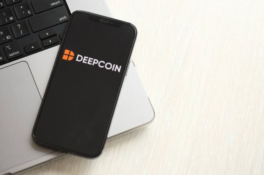 KYIV, UKRAINE - 15 Mart 2024 MacBook panelinde iPhone ekranında Deepcoin logosu. Kripto döviz portalı