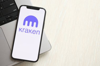 KYIV, UKRAINE - 15 Mart 2024 Kraken logosu MacBook panelinde iPhone ekranında. Kripto döviz portalı