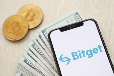 KYIV, UKRAINE - 15 Mart 2024 Bitget logosu iPhone ekranında dolar ve bitcoin ile birlikte. Kripto döviz portalı