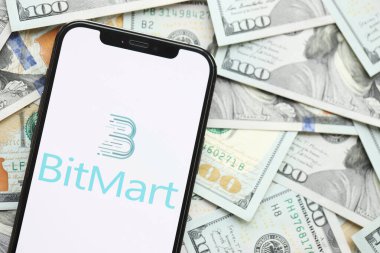 KYIV, UKRAINE - 15 Mart 2024 Bitmart logosu iPhone ekranında yüzlerce dolarlık banknotlarla. Kripto döviz portalı