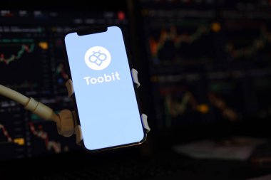 KYIV, UKRAINE - iPhone ekranında 15 Mart 2024 Toobit logosu ve kripto para birimi değer grafikleri. Kripto döviz portalı