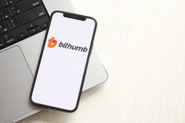KYIV, UKRAINE - 15 Mart 2024 Bithumb logosu MacBook panelinde iPhone ekranında. Kripto döviz portalı
