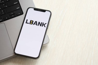 KYIV, UKRAINE - 15 Mart 2024 Lbank logosu MacBook panelinde iPhone ekranında. Kripto döviz portalı