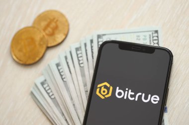 KYIV, UKRAINE - 15 Mart 2024 Bitrue logosu iPhone ekranında dolar ve bitcoin ile birlikte. Kripto döviz portalı