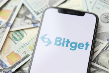 KYIV, UKRAINE - 15 Mart 2024 Bitget logosu iPhone ekranında yüzlerce dolarlık banknotlarla. Kripto döviz portalı