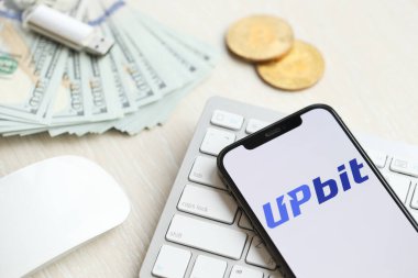 KYIV, UKRAINE - 15 Mart 2024 Upbit logosu iPhone ekranında beyaz klavyede para ve bitcoin ile. Kripto döviz portalı