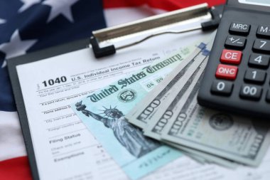United States 1040 tax form individual income tax return with refund check and US dollar bills close up clipart