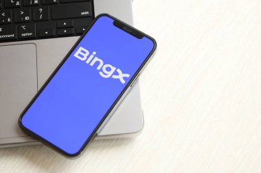 KYIV, UKRAINE - 15 Mart 2024 MacBook panelindeki iPhone ekranında BingX logosu. Kripto döviz portalı