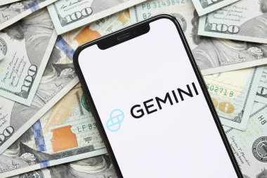 KYIV, UKRAINE - 15 Mart 2024 Gemini logosu iPhone ekranında yüzlerce dolarlık banknotlarla. Kripto döviz portalı
