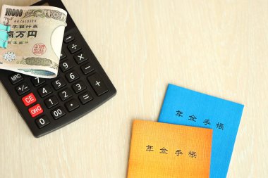 Japon emeklilik sigortası broşürleri yeni para faturaları ve hesap makineleri ile masaya yakın.