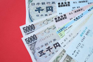 Açık mavi ve kırmızı Japon Sağlık Sigortası kartları Japon ikamet kartı ve telefon kartımla birlikte masada.