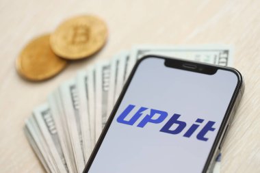 KYIV, UKRAINE - 15 Mart 2024 Upbit logosu iPhone ekranında dolar ve bitcoin ile birlikte. Kripto döviz portalı