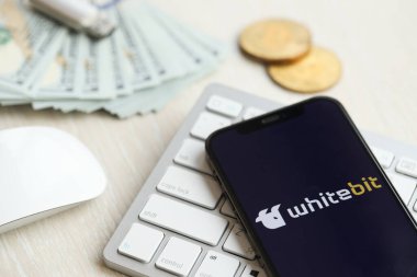 KYIV, UKRAINE - 15 Mart 2024 Whitebit logosu iPhone ekranında beyaz klavyede para ve bitcoin ile. Kripto döviz portalı