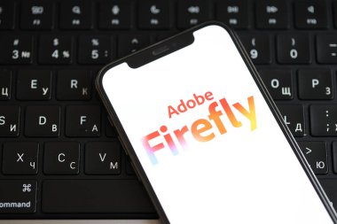 KYIV, UKRAINE - 17 Mart 2024 Adobe Firefly logosu iPhone ekranda ve MacBook klavyesinde. Yapay Zeka Motoru